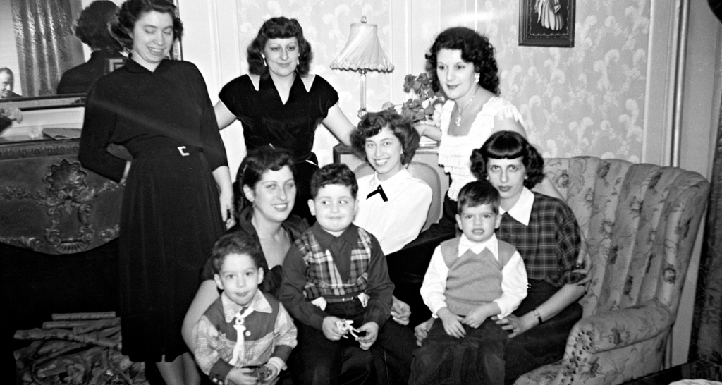 Family photo of 6 smiling women with children, seated and standing
