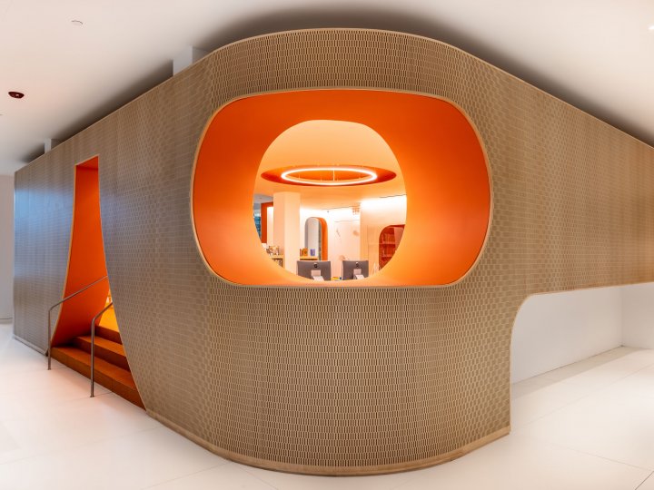 A corner shot of the Adams Street Library children's section looking from the main entrance. The wall is curved and textured wood and the opening window into the children's section is orange.