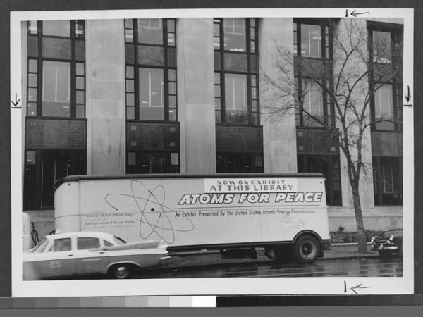 Exterior view of large van, parked on Flatbush Avenue near Brooklyn Public Library's Central Library, with large sign, 